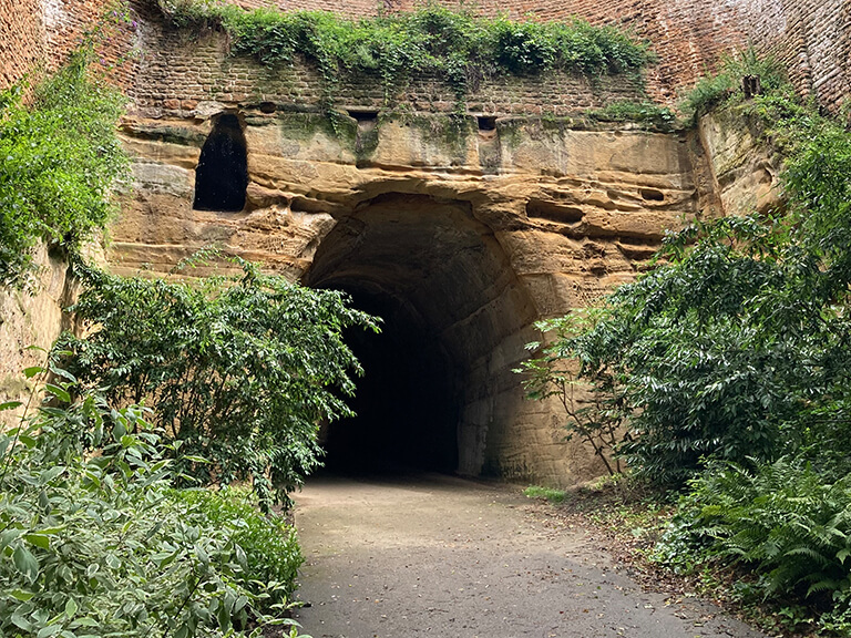 A tunnel in Nottingham, carved in sandstone, surrounded by trees and folliage